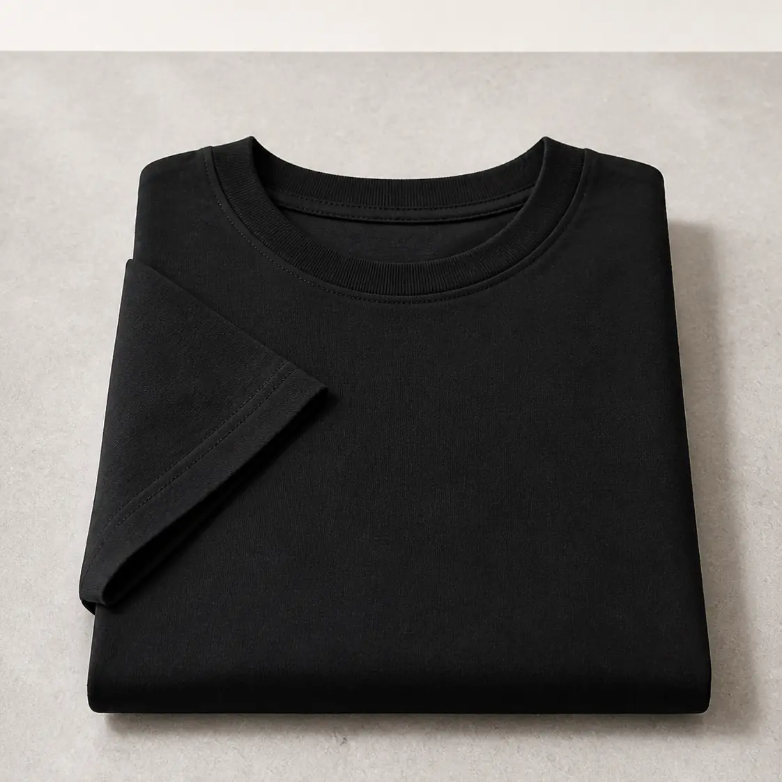 Black everyday tee folded on a light surface